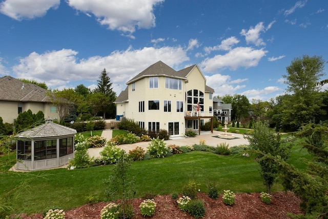 back of house with a yard, a sunroom, a patio, and stucco siding