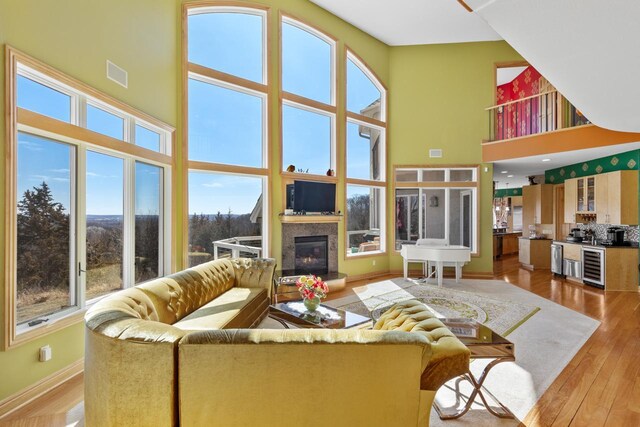 living room featuring plenty of natural light, wine cooler, a high ceiling, and wood-type flooring