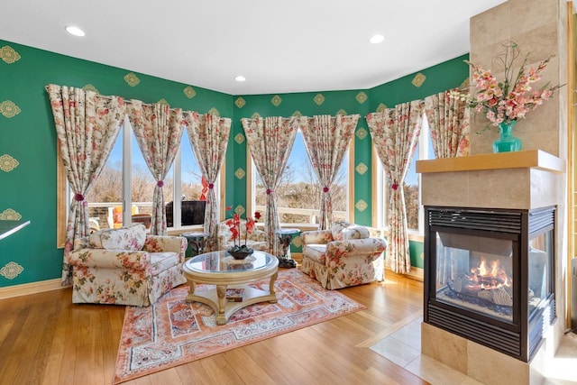 living area with baseboards, wood finished floors, a multi sided fireplace, and recessed lighting
