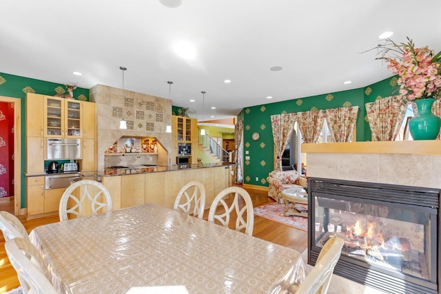 dining room featuring a fireplace, light wood-type flooring, stairs, and recessed lighting