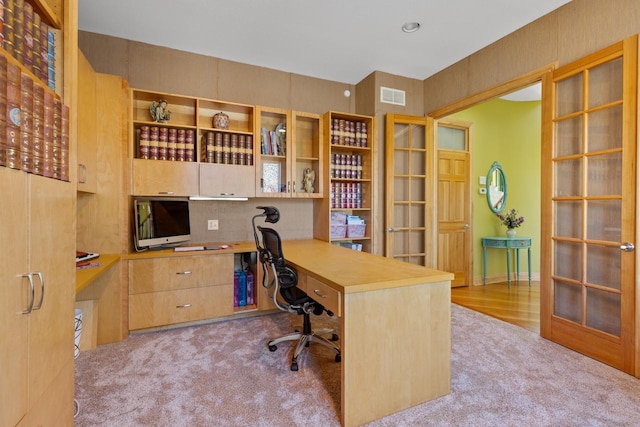 carpeted office space with built in desk, visible vents, and french doors