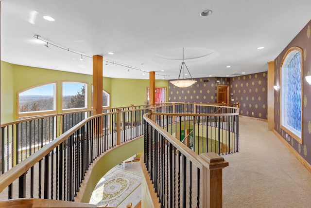 hall featuring wallpapered walls, plenty of natural light, carpet flooring, and an upstairs landing