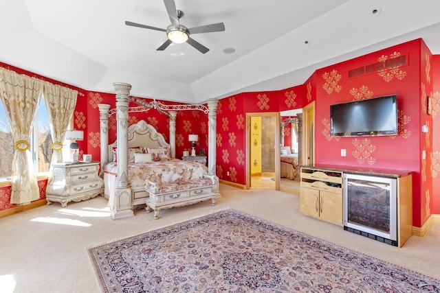 bedroom with carpet floors, beverage cooler, ensuite bathroom, and ornate columns