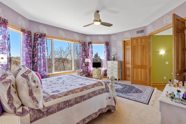 carpeted bedroom featuring a ceiling fan and visible vents