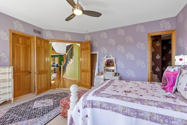 bedroom with wallpapered walls, visible vents, and a ceiling fan