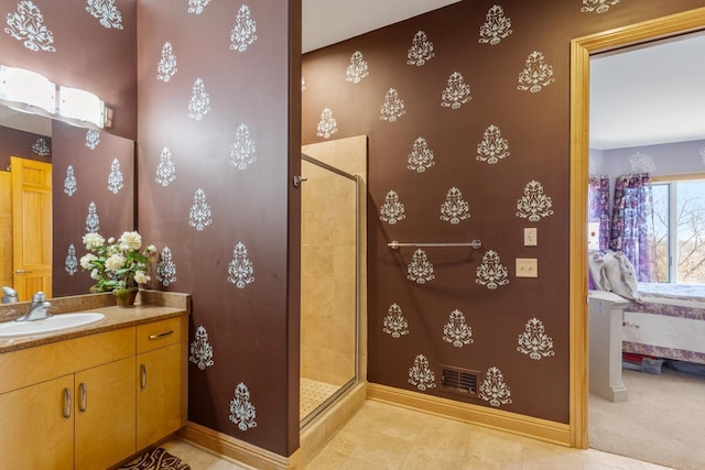 ensuite bathroom featuring baseboards, vanity, connected bathroom, and a stall shower