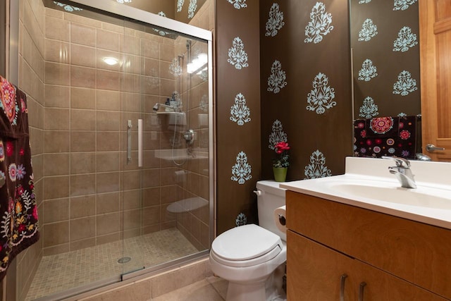 bathroom featuring a shower stall, toilet, and vanity