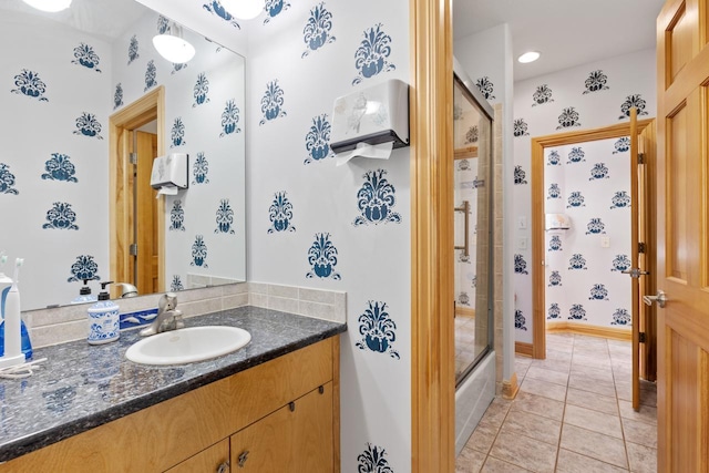 full bathroom featuring baseboards, vanity, tile patterned flooring, and bath / shower combo with glass door