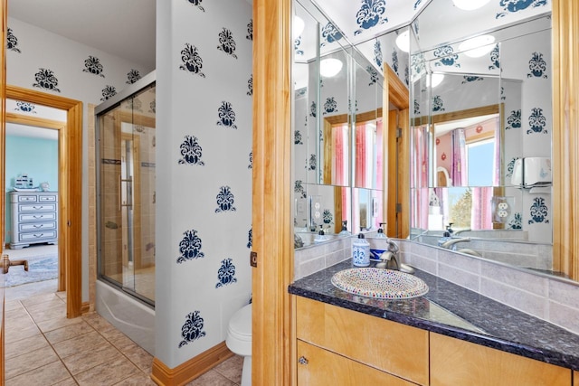 bathroom with vanity, baseboards, enclosed tub / shower combo, toilet, and tile patterned flooring