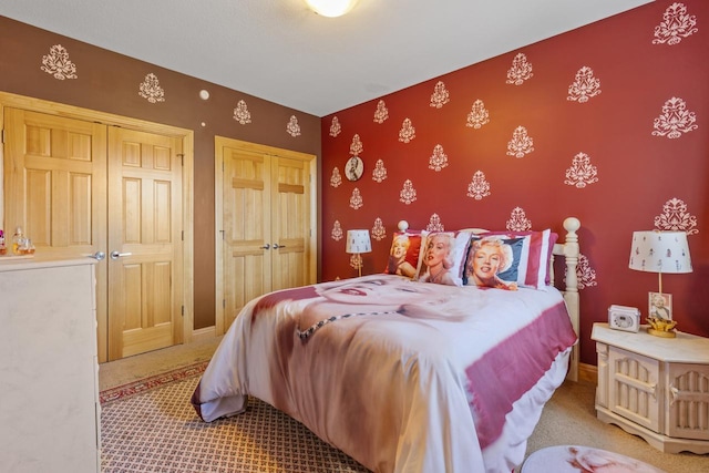 bedroom with carpet floors, an accent wall, wallpapered walls, and baseboards