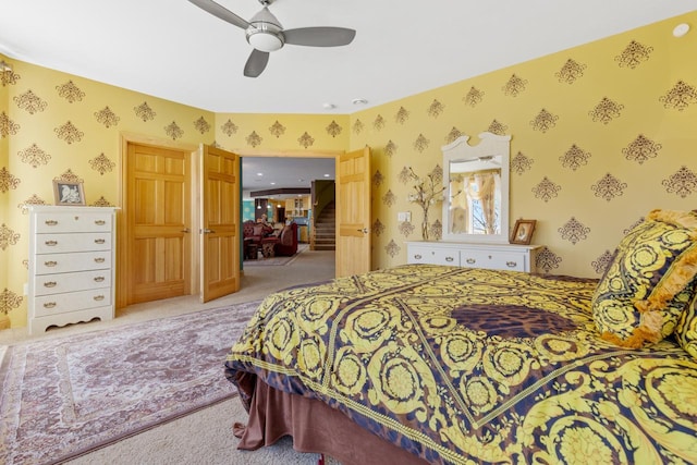 bedroom featuring wallpapered walls, light colored carpet, and ceiling fan