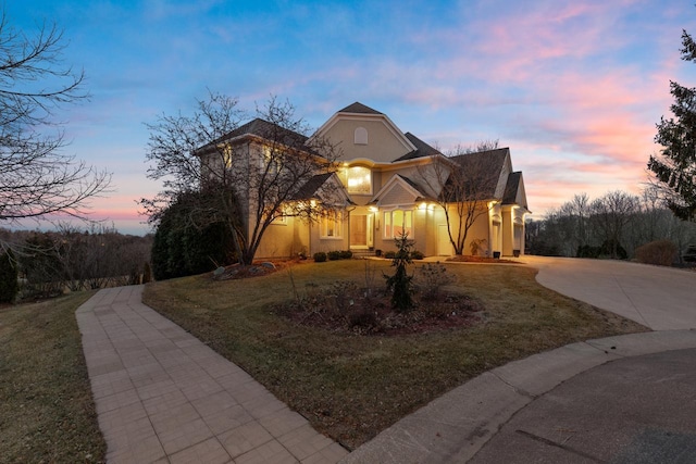 traditional-style home featuring stucco siding, a front yard, and curved driveway