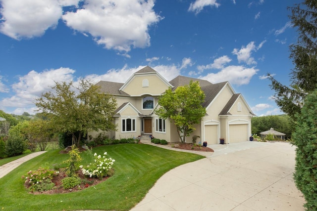 view of front of home with stucco siding, concrete driveway, a front yard, and a garage