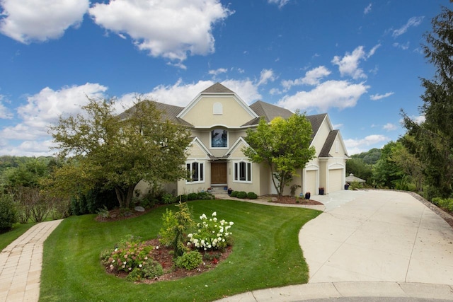 view of front facade featuring stucco siding, an attached garage, a front lawn, and concrete driveway