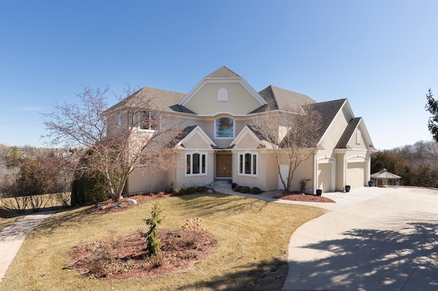 traditional home featuring a garage, stucco siding, a front yard, and concrete driveway