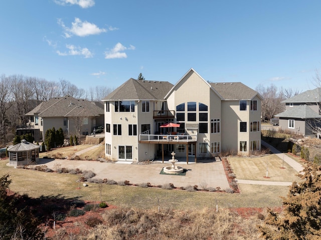 back of property with a wooden deck, a patio area, and stucco siding