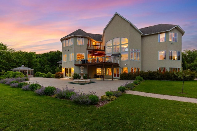 19115 Vogel Farm Trl, Eden Prairie, MN 55347 - rear view of house featuring a yard, stucco siding, curved driveway, a balcony, and a patio
