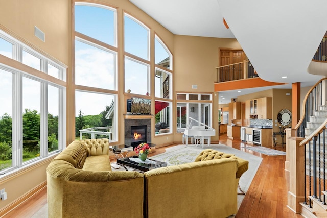 19115 Vogel Farm Trl, Eden Prairie, MN 55347 - living room with a glass covered fireplace, a high ceiling, beverage cooler, stairway, and light wood finished floors