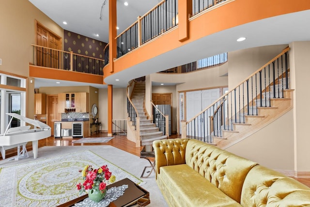 19115 Vogel Farm Trl, Eden Prairie, MN 55347 - living area featuring wine cooler, a high ceiling, stairs, wood finished floors, and recessed lighting