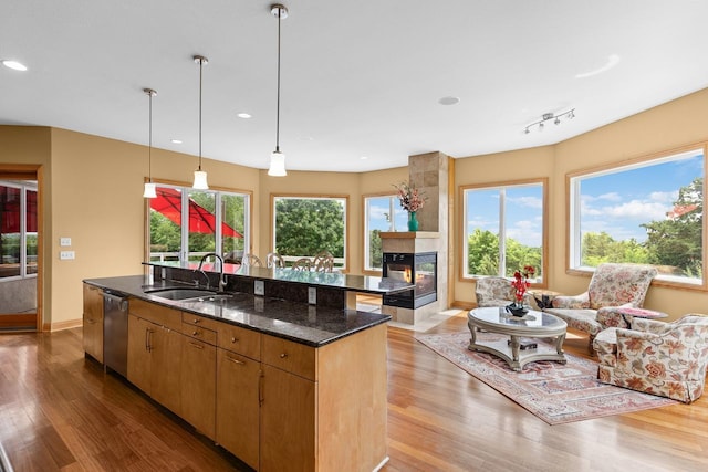 19115 Vogel Farm Trl, Eden Prairie, MN 55347 - kitchen with stainless steel dishwasher, light wood-type flooring, a center island with sink, dark stone counters, and recessed lighting