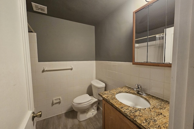 bathroom with tile walls, hardwood / wood-style floors, vanity, toilet, and walk in shower