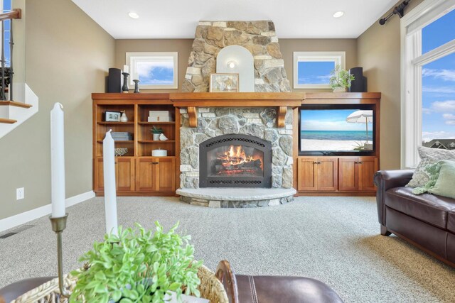 carpeted living area with baseboards, visible vents, and a fireplace
