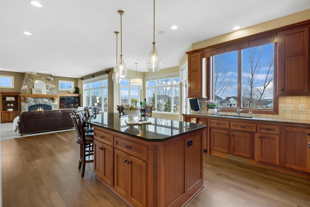 kitchen featuring brown cabinets, a sink, a fireplace, wood finished floors, and tasteful backsplash