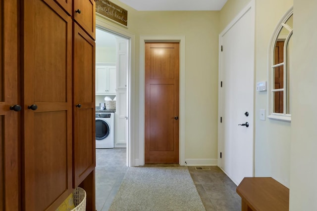 hallway with baseboards, washer / dryer, and visible vents