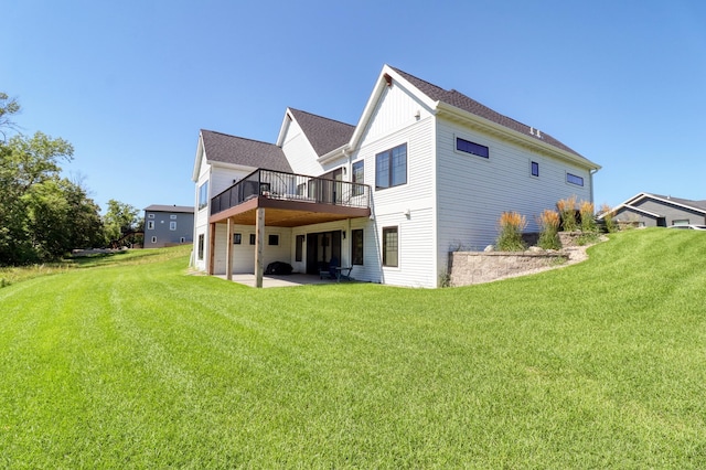 rear view of house featuring a wooden deck, a lawn, and a patio area