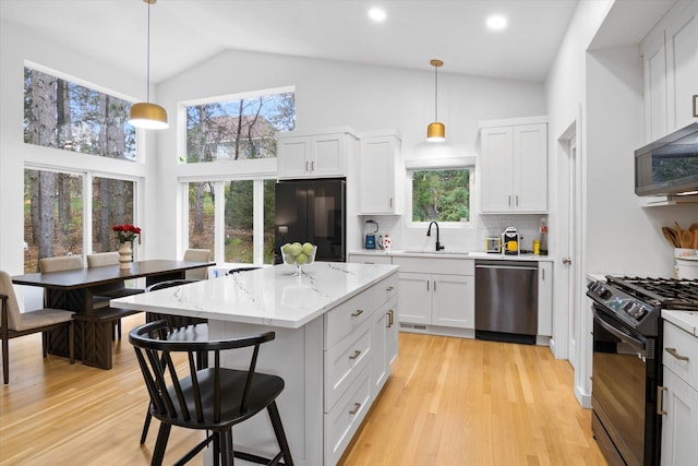 kitchen featuring sink, white cabinetry, decorative light fixtures, a center island, and black appliances