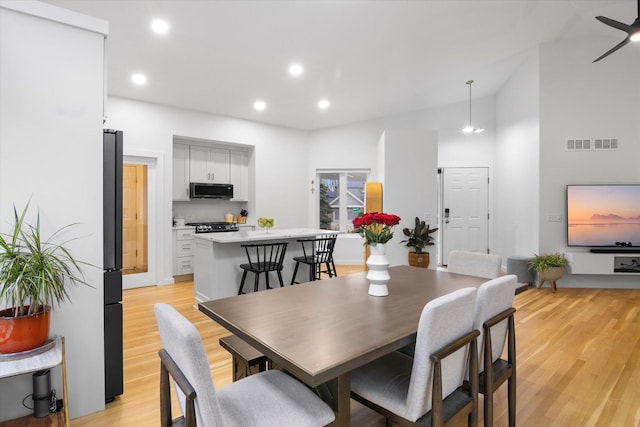 dining space featuring light hardwood / wood-style floors and a high ceiling