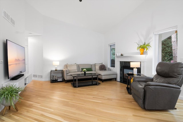 living room with wood-type flooring, a high end fireplace, and high vaulted ceiling