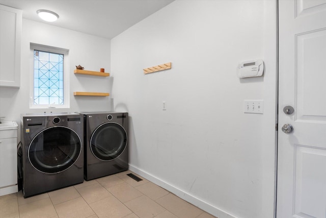 washroom featuring cabinets, washing machine and dryer, and light tile patterned flooring