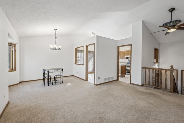 spare room featuring baseboards, visible vents, light colored carpet, lofted ceiling, and a textured ceiling