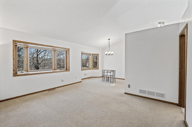 unfurnished room with carpet floors, lofted ceiling, visible vents, a textured ceiling, and a chandelier