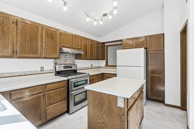 kitchen with lofted ceiling, range with two ovens, under cabinet range hood, light countertops, and tasteful backsplash