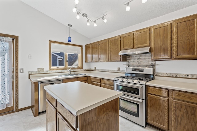 kitchen with light countertops, appliances with stainless steel finishes, vaulted ceiling, a sink, and under cabinet range hood