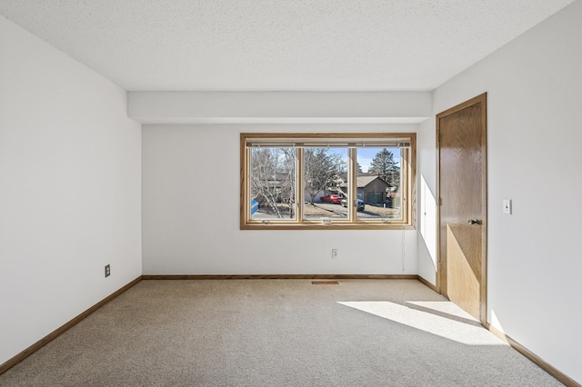 spare room with carpet flooring, a textured ceiling, and baseboards