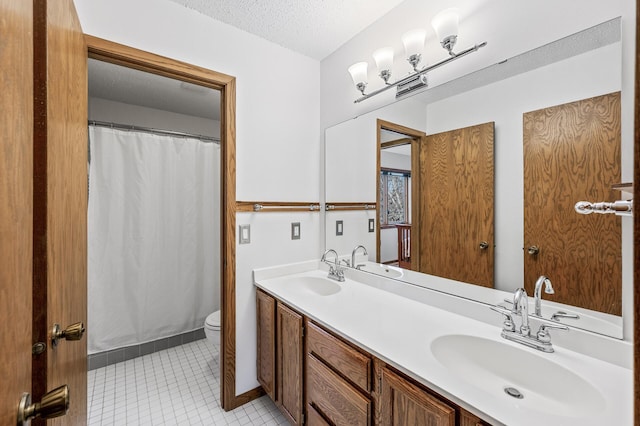 bathroom with toilet, double vanity, a textured ceiling, and a sink