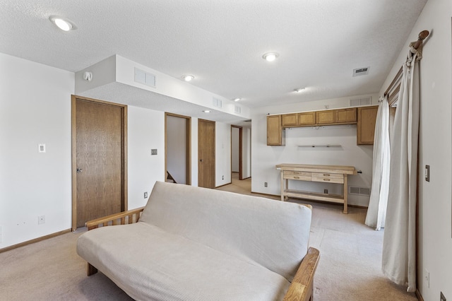 living area with light colored carpet, visible vents, a textured ceiling, and baseboards