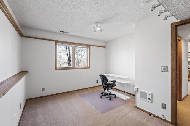 unfurnished office with carpet floors, baseboards, visible vents, and a textured ceiling