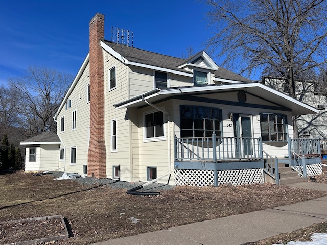 view of front of house with a chimney and roof with shingles