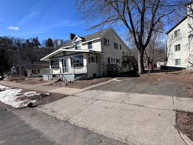 view of front of house with driveway, a porch, and a chimney