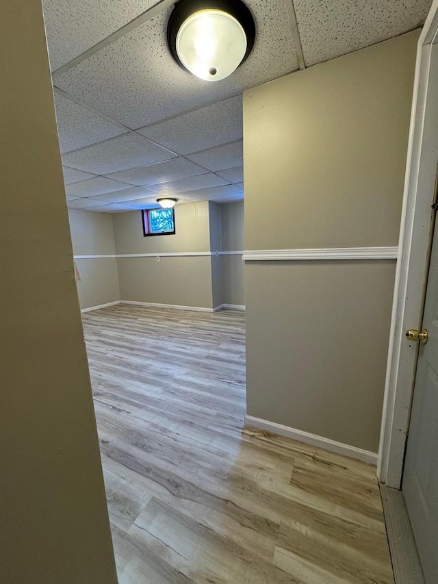 spare room featuring baseboards, a drop ceiling, and wood finished floors