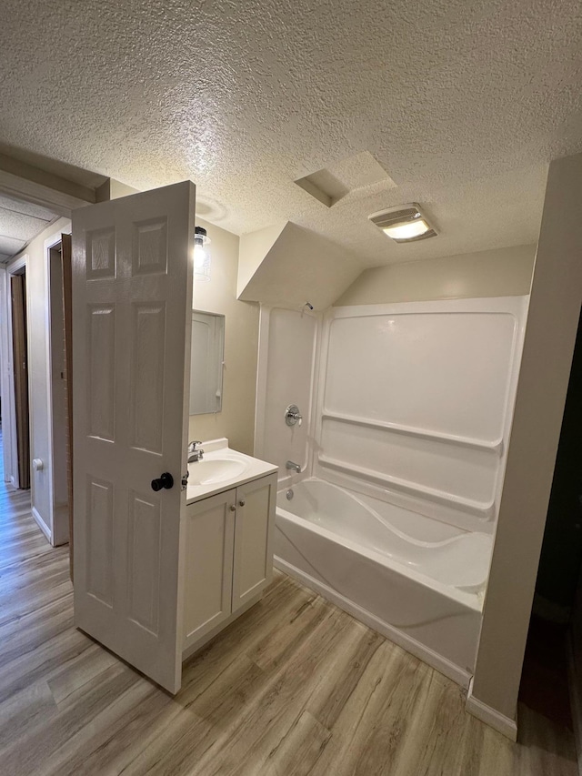 full bathroom featuring a textured ceiling, washtub / shower combination, wood finished floors, and vanity