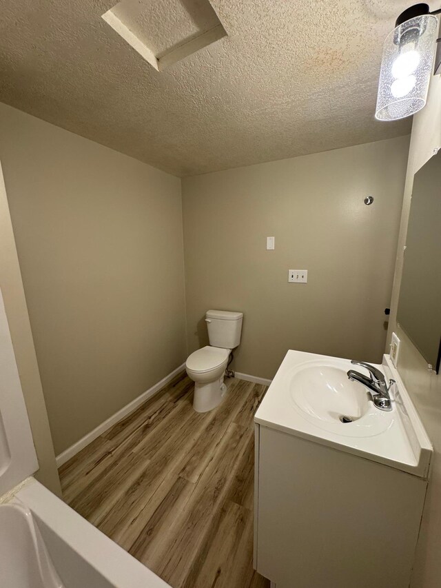 bathroom with vanity, a textured ceiling, toilet, and wood finished floors