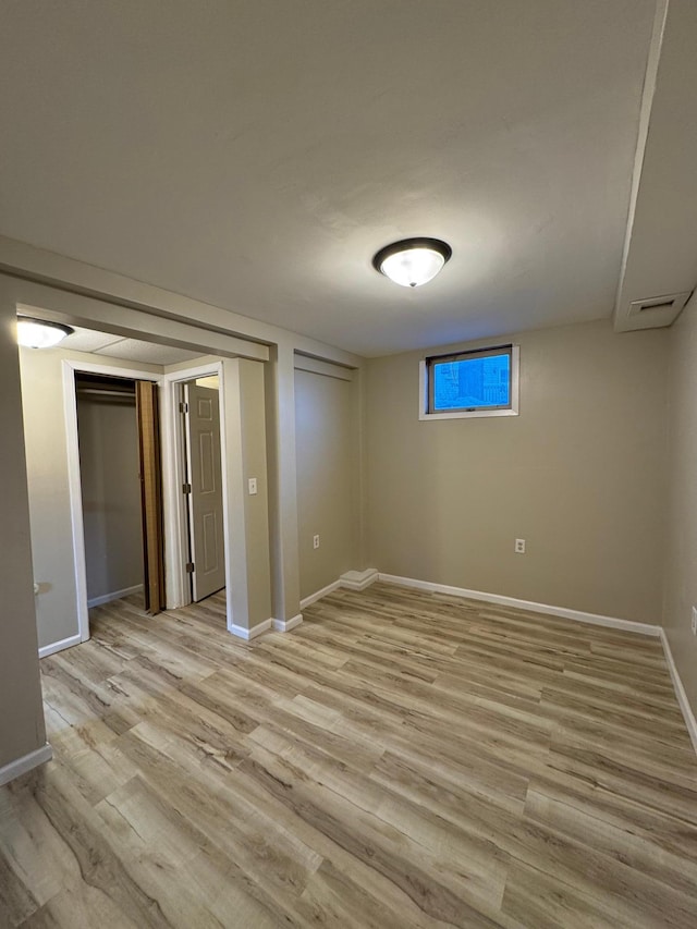 basement with light wood-type flooring and baseboards