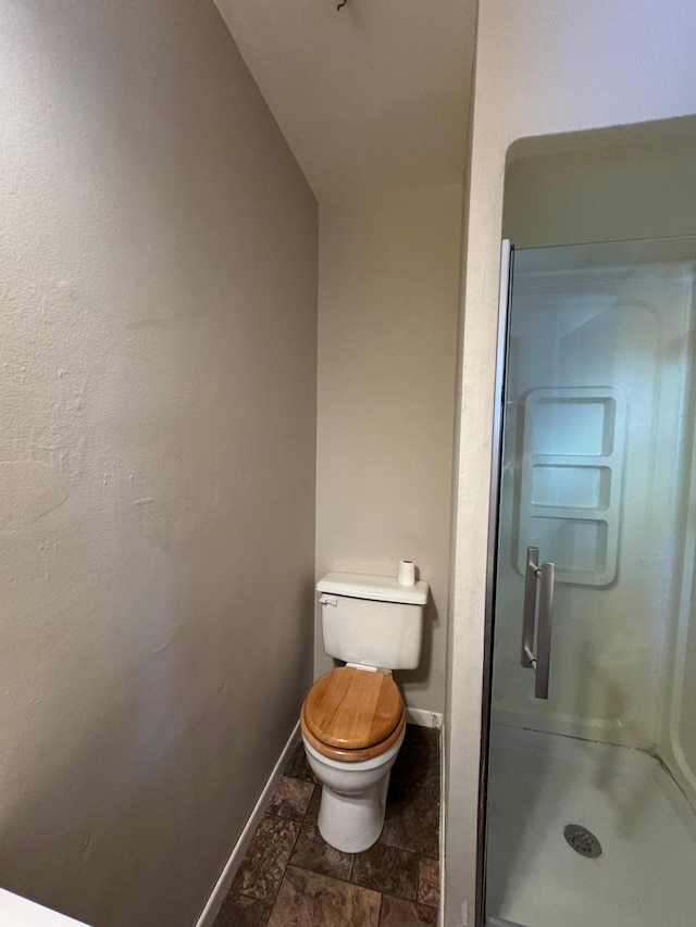 bathroom with toilet, a shower stall, and baseboards