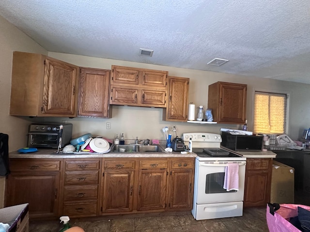 kitchen with electric stove, brown cabinetry, a sink, and visible vents