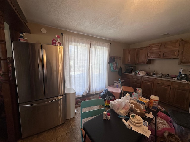 kitchen with a textured ceiling, tile patterned flooring, a sink, light countertops, and freestanding refrigerator